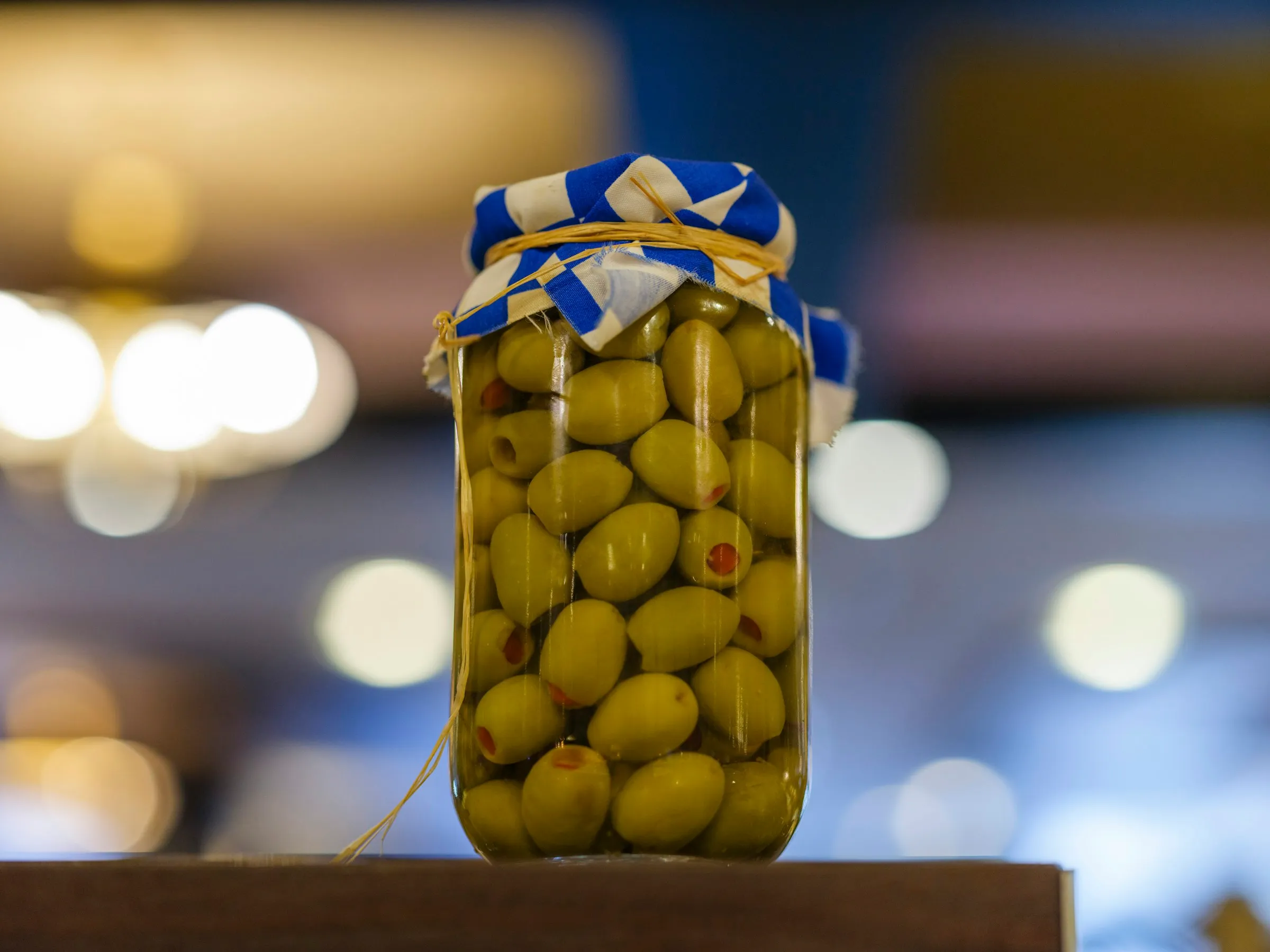 Ağzı kumaşla bağlanmış bir kavanozda yeşil sofralık zeytin